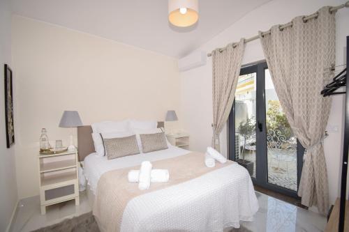 a bedroom with a bed with white sheets and a window at White Star Estoril in Estoril