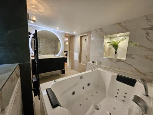 La salle de bains est pourvue d'une grande baignoire blanche et d'un lavabo. dans l'établissement Charmante Maisonette du Lot rénovée avec balnéo, à Latouille-Lentillac