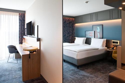 two pictures of a hotel room with a bed and a desk at Holiday Inn - Hamburg - HafenCity by IHG in Hamburg