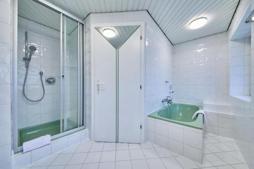 a bathroom with a shower and a green tub at Platzhirsch Rooms - B&B - SELF CHECK-IN in Piesendorf