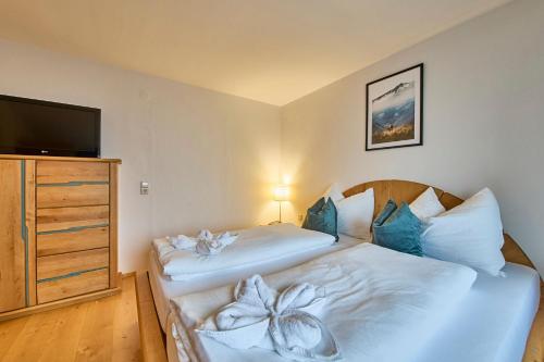 two beds in a room with a tv and a bedskirtspectspectspectspects at Platzhirsch Rooms - B&B - SELF CHECK-IN in Piesendorf