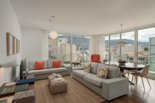 a living room with a couch and a table and some windows at The Plaza Apartment in Funchal