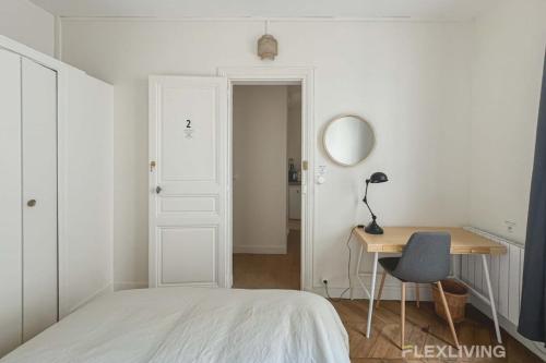 une chambre avec un lit, un bureau et un miroir dans l'établissement Flexliving - Room - Mesnil, à Paris