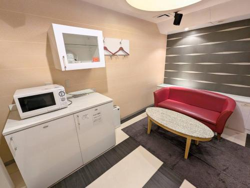 a small room with a red chair and a microwave at もしもしピエロ 泉大津新館 in Izumiotsu