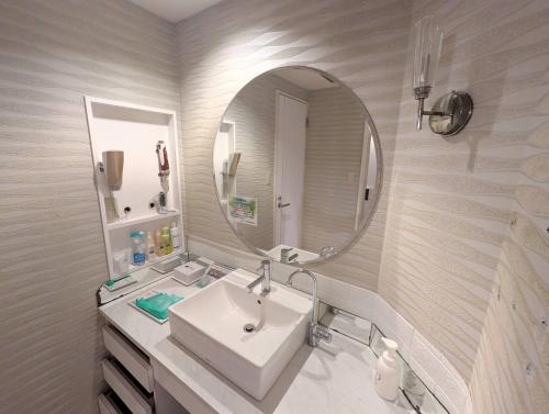 a bathroom with a sink and a mirror at もしもしピエロ 泉大津新館 in Izumiotsu