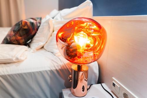 a lamp on a table next to a bed at Science Hotel Prémium in Szeged