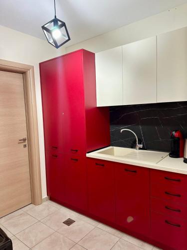 a red kitchen with white cabinets and a sink at Endless Blue Garden Villa in Paleo Tsifliki