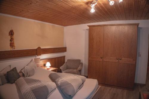 a bedroom with a bed and a cabinet and a chair at Haus Bergwind in Sankt Leonhard im Pitztal