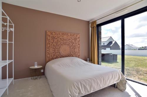 a bedroom with a bed and a large window at Cosy Fréhel - Maison moderne proche du bourg in Frehel