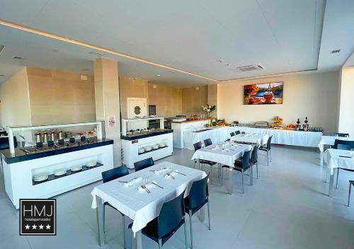 a restaurant with white tables and chairs and a kitchen at Hotel Spa Mirador in Jorquera