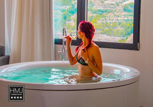 a woman in a bath tub drinking a glass of wine at Hotel Spa Mirador in Jorquera