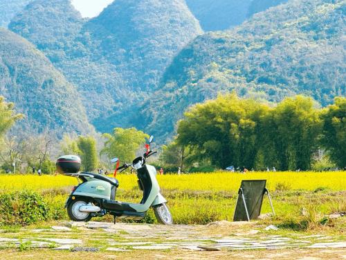 a scooter parked in a field with mountains in the background at CANG 藏In山院 in Yangshuo