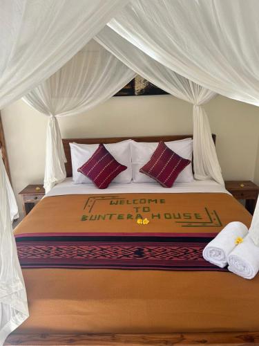 a bedroom with a bed with a canopy with pillows at Buntera Homestay Sidemen in Sidemen