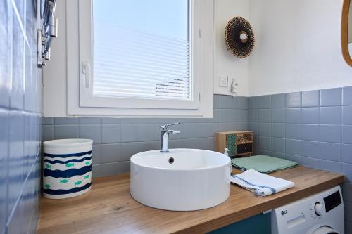 une salle de bain avec un lavabo blanc et une fenêtre dans l'établissement La Halte Sainte-Catherine - A 15 min de la plage, à Honfleur