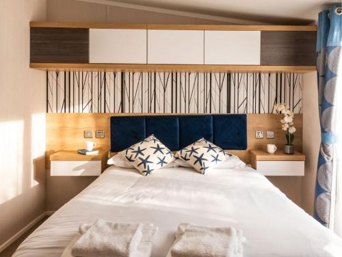 a bedroom with a large white bed with two pillows at Pinewoods Saltmarsh Lodge sleeps 7 – no.1 in Wells next the Sea