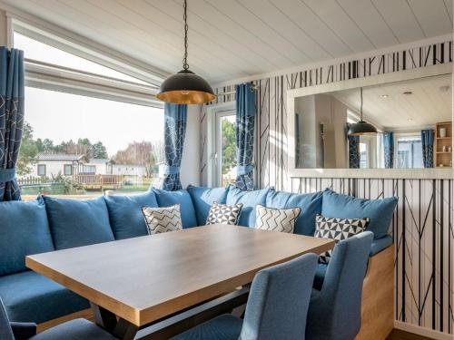 a dining room with a blue couch and a wooden table at Pinewoods Saltmarsh Lodge no.2 sleeps 7 – no dogs in Wells next the Sea