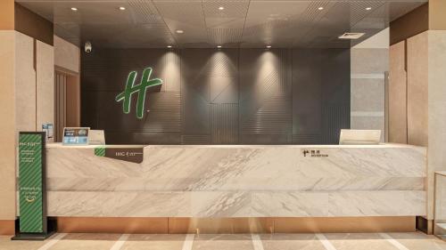 a reception desk in a lobby with a sign on the wall at Holiday Inn Dujiangyan Ancient Town by IHG in Dujiangyan