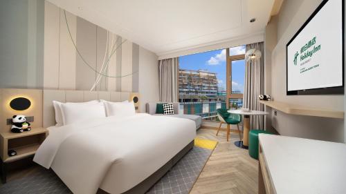 a hotel room with a large bed and a flat screen tv at Holiday Inn Dujiangyan Ancient Town by IHG in Dujiangyan