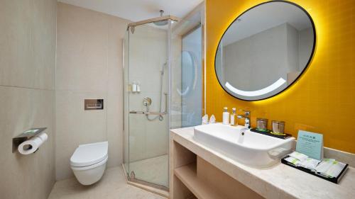 a bathroom with a sink and a toilet and a mirror at Holiday Inn Dujiangyan Ancient Town by IHG in Dujiangyan