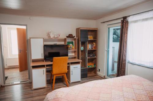 a bedroom with a bed and a desk with a television at Bungalow Donaublick mit Pool und Garten in Sankt Nikola an der Donau