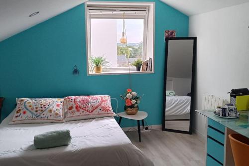 - une chambre avec des murs bleus et un lit avec un miroir dans l'établissement Le regard bleu, à Rennes