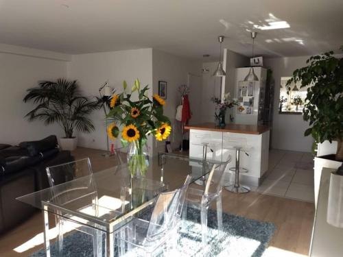 un salon avec une table en verre et une cuisine dans l'établissement Le regard bleu, à Rennes