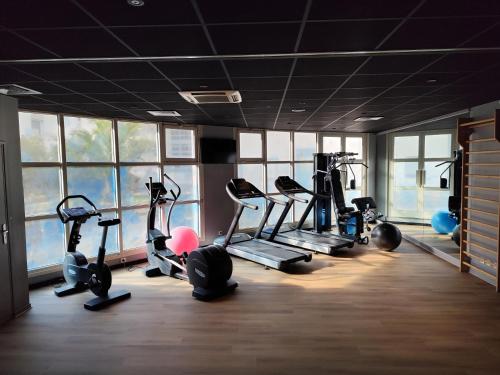 a gym with several tread machines in a room with windows at ibis Le Havre Centre in Le Havre