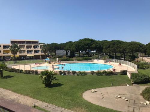 une grande piscine avec des personnes dans un parc dans l'établissement Studio Anny climatisé vue mer avec piscine, au Grau-du-Roi