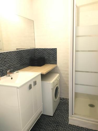 une salle de bain avec un lavabo et une machine à laver dans l'établissement Studio Anny climatisé vue mer avec piscine, au Grau-du-Roi