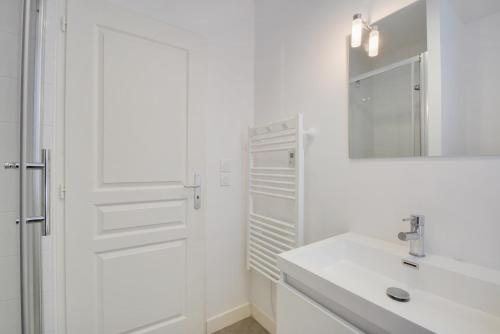 een witte badkamer met een wastafel en een spiegel bij Le Cœur des Dominicains - pour 6 centre de Nancy in Nancy