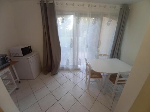 une table blanche et des chaises dans une cuisine avec une fenêtre dans l'établissement Studio village de vacances, à Arles