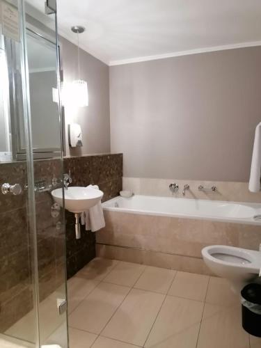 a bathroom with a tub and a sink and a toilet at Mandela Rhodes Place in Cape Town