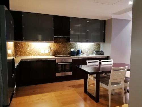 a kitchen with black cabinets and a table and chairs at Mandela Rhodes Place in Cape Town