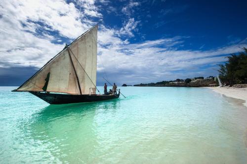 a sail boat in the water on a beach at OceanView Penthouse Mirage ZanzibarHouses in Kiwengwa