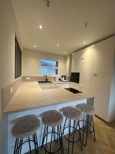 une cuisine avec trois tabourets de bar devant un comptoir dans l'établissement Spacieux et Moderne T2 près du centre, à Cannes