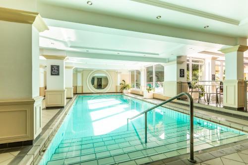 a swimming pool in a hotel lobby with a swimming poolvisorvisor at Wunsch Hotel Mürz - Natural Health & Spa Hotel in Bad Füssing