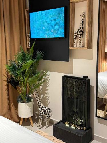 a room with a tv and giraffes and a plant at Contessa Suites in Lefkada Town