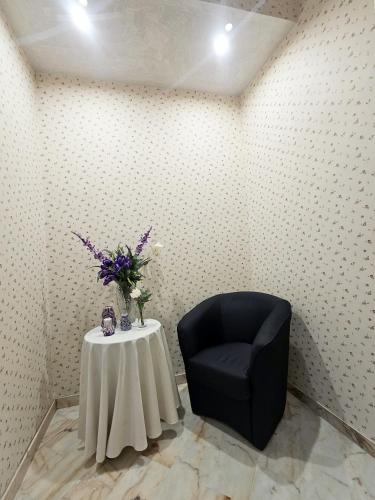 a black chair and a table with a vase of flowers at Domus Clara - guest house Venosa in Venosa