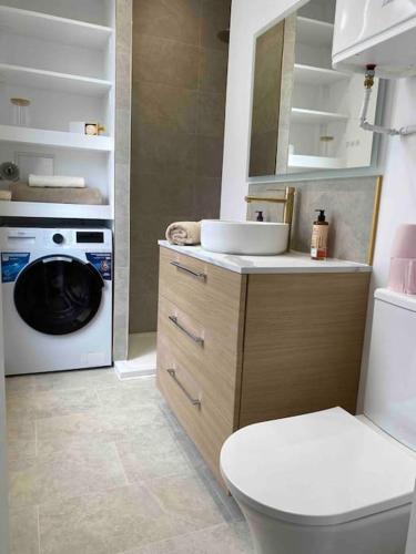 La salle de bains est pourvue de toilettes et d'un lave-linge. dans l'établissement Appartement - Cozy - 10 min de Paris, à Levallois-Perret