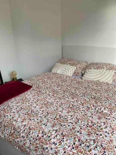 - une chambre avec un lit et une couette en fleurs dans l'établissement Appartement - Cozy - 10 min de Paris, à Levallois-Perret