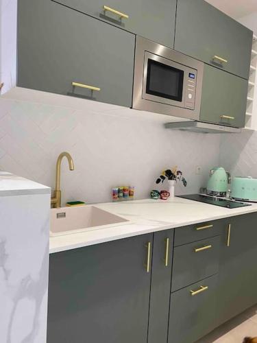 une cuisine avec un évier et un micro-ondes dans l'établissement Appartement - Cozy - 10 min de Paris, à Levallois-Perret