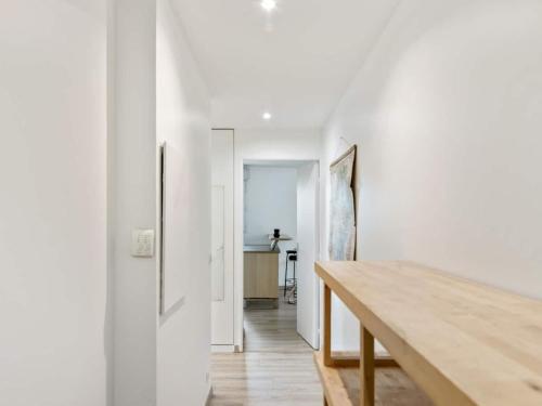 un couloir avec des murs blancs et une table en bois dans l'établissement Chambre à 100m du Stade de France, à Saint-Denis
