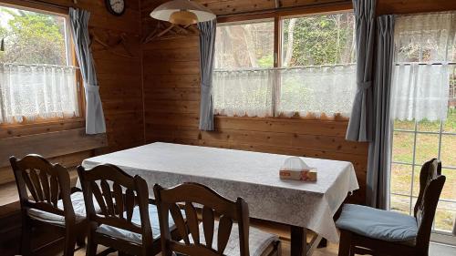 a dining room with a table and chairs and windows at Grass Hopper in Karuizawa
