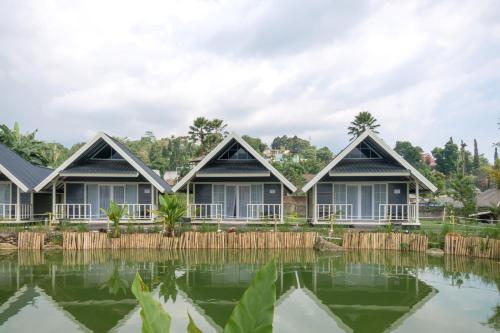 a row of cottages next to a pond at Salma Syariah by TwoSpaces, Bogor in Jakarta