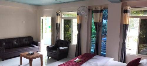 a bedroom with a bed and a chair and windows at Shatsngi Home Stay in Dawki
