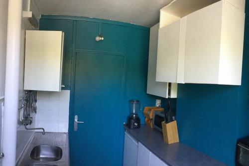 une cuisine avec des placards bleus et blancs dans l'établissement Appartement entier résidence calme à Rueil- Proche Paris, à Rueil-Malmaison
