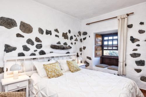 1 dormitorio con 1 cama blanca con rocas en la pared en Sombrero de Pico A, en El Paso