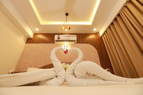 two towels shaped like swans sitting on a bed at Liwa Tower Hotel & Business Center in Kunnamkulam