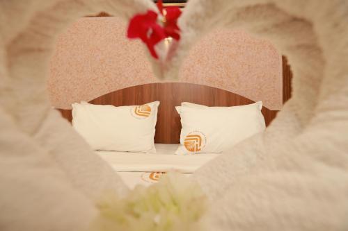a bed with white pillows and a wooden headboard at Liwa Tower Hotel & Business Center in Kunnamkulam
