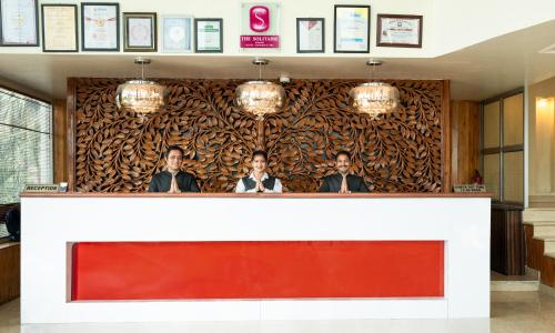 a wall with three men standing behind a counter at Pride Premier Solitaire in Dehradun